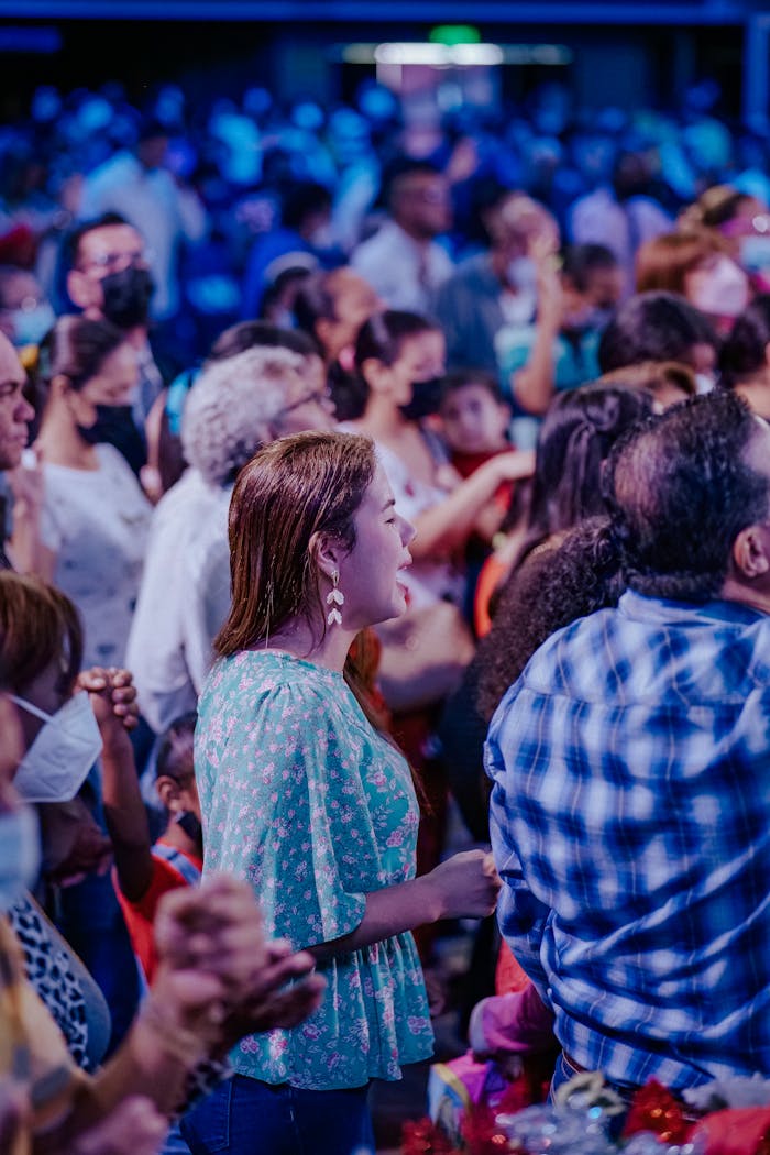 services-02 A lively crowd stands together at an indoor event under dramatic blue lighting.