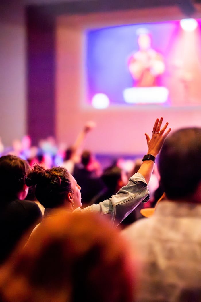 who-we-are Vibrant concert scene with audience engaged, hand raised in excitement.